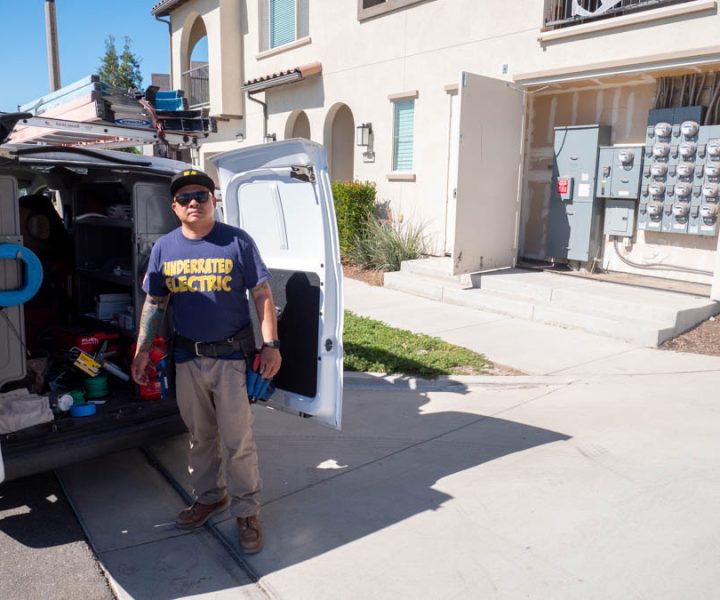 A professional electrician inspects a large commercial electrical panel, highlighting expertise in commercial electrical maintenance.