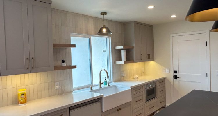 A sleek, modern kitchen showcasing effective recessed lighting, complementing the clean, functional design with grey cabinetry and a bright workspace.